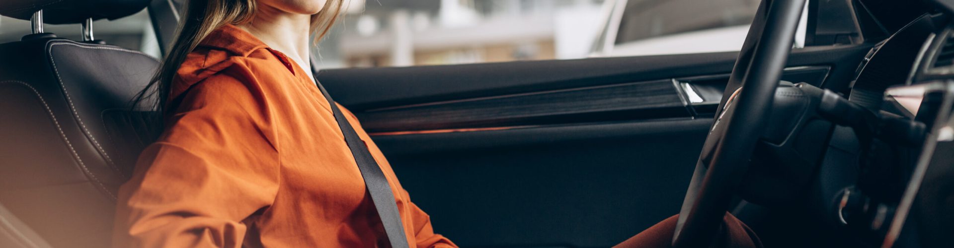 Woman buckles up the safety belt in a car